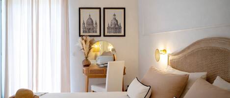 Habitación de hotel con cama, escritorio y silla, lámpara y dos cuadros en la pared.