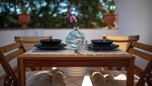 Un tavolo da pranzo con un vaso di fiori, piatti neri e un bicchiere d'acqua.