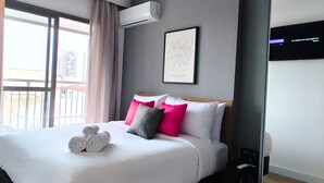 Ein modernes Hotelzimmer mit einem großen Bett, einem Spiegel und einem Fenster mit Vorhängen.