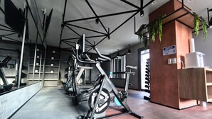 Ein Fitnessraum mit Ergometer, Spiegeln und einem Holzbüro.