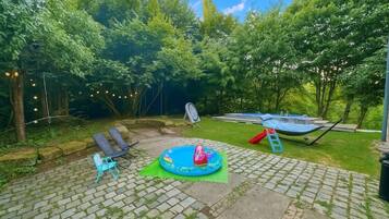 Ein Garten mit einem kleinen aufblasbaren Pool, einer Hängematte und einem Boot.