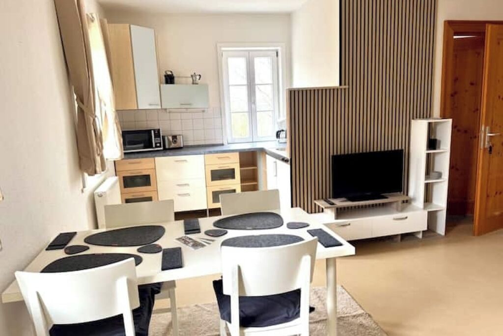 Een moderne keuken met witte kastjes, een inbouwmagnetron en een flatscreen televisie.