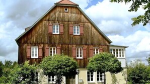 A large wooden house with multiple windows and a sloped roof. - Cozy vacation apartment in the countryside (Sulzbach-Laufen)