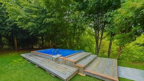 En trädgård med en pool, ett trädäck och omgivande grönska.