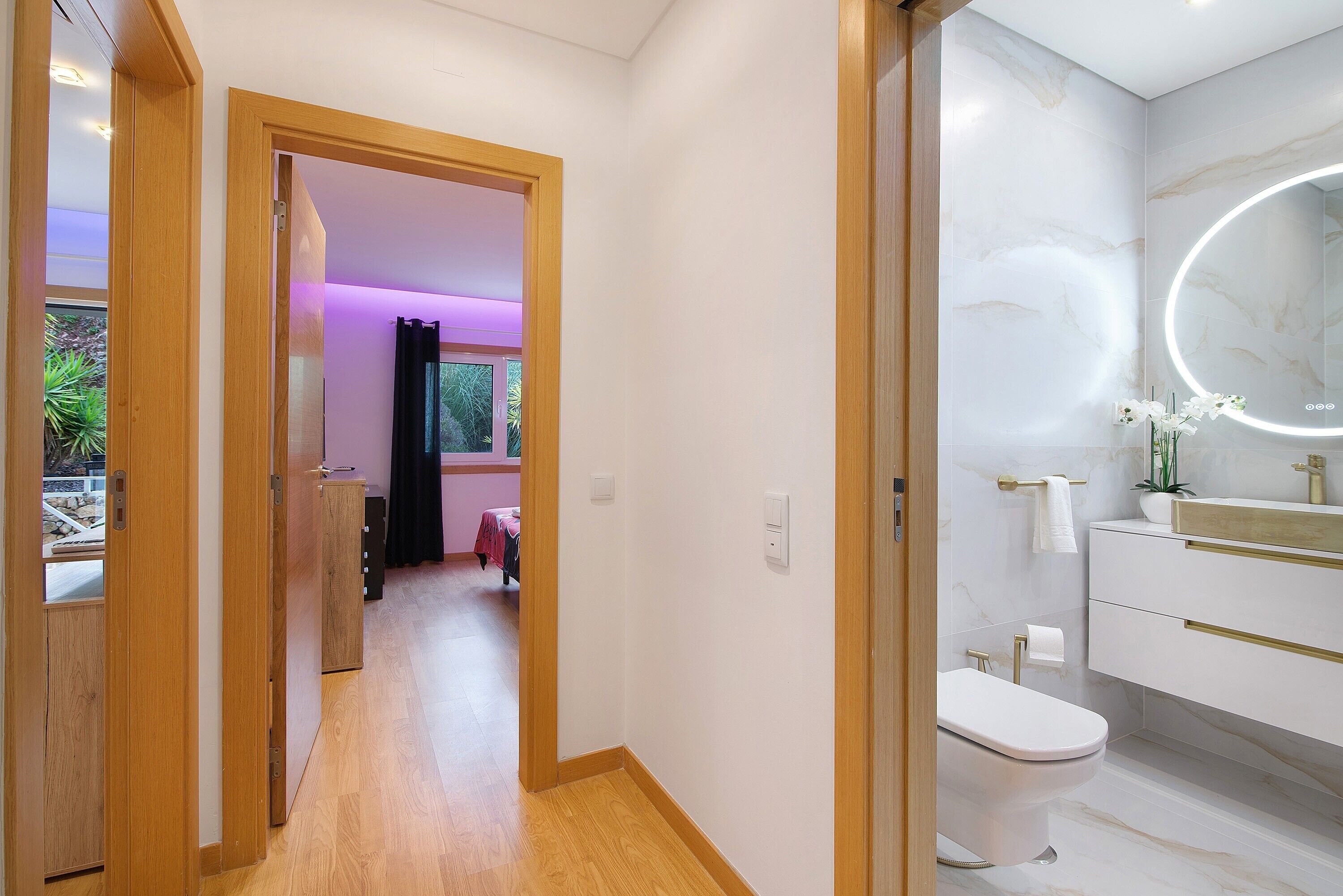 Een moderne badkamer met toilet, wastafel en een grote spiegel.