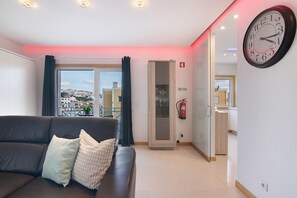 Un salon moderne avec un canapé, une grande fenêtre et une vue sur la ville.