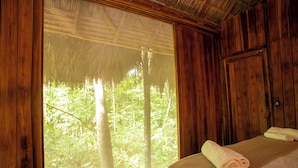A wooden room with a large window, a bed with a rolled towel, and a wooden wardrobe. - Ecoaraguaia Jungle Lodge (Caseara)
