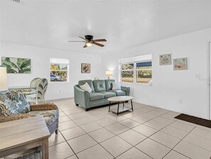 A spacious living room with a light blue sofa, a wooden coffee table, and a ceiling fan. - Tarpon Trailside close to all the fun available in Historic Tarpon Springs! (Tarpon Springs)