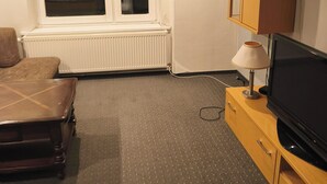 Ein Hotelzimmer mit Bett, Schreibtisch, Fernseher und einem Fenster mit Jalousien.