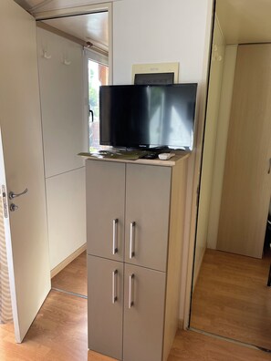 A room with a television on a cabinet, a door, and a window. - Relaxing stay in an air-conditioned bungalow - Quiet campsite close to the sea (Port-la-Nouvelle)