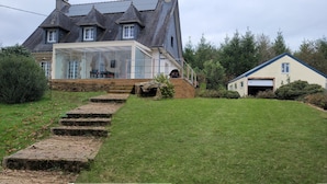 A house with a large glass conservatory, a stone staircase, and a well-maintained lawn. - Au Pré du Chêne (Le Faouët)