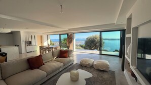A modern living room with a sofa, ottomans, a coffee table, and a TV. - 180°C sea Giens peninsula (Carqueiranne)