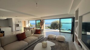 A modern living room with a sofa, ottomans, a coffee table, and a TV. - 180°C sea Giens peninsula (Carqueiranne)