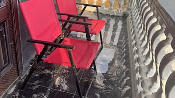 A balcony with two red chairs and a decorative balustrade.