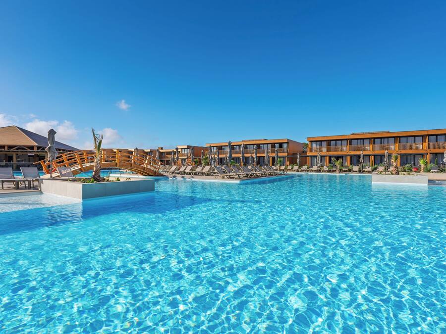 Ein Resort mit einem großen Schwimmbad, Liegestühlen und einem Gebäude mit Balkonen.