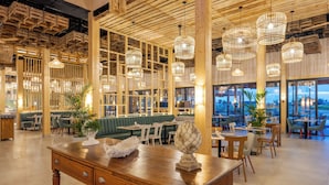 A spacious restaurant with wooden furniture, hanging wicker chandeliers, and large windows offering a view. - Pestana Dunas All Inclusive Eco Resort (Porto Santo)
