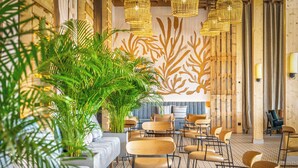 A modern interior with wooden walls, a seating area with tables and chairs, and hanging wicker lamps. - Pestana Dunas All Inclusive Eco Resort (Porto Santo)