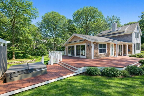 A two-story house with a covered patio, a chimney, and a stone foundation.