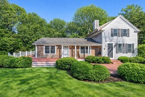 A two-story house with a front porch, brick foundation, and a separate garage.