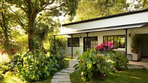 Una casa moderna con un camino de piedra que lleva a la entrada, rodeada de abundante vegetación y un césped bien cuidado.