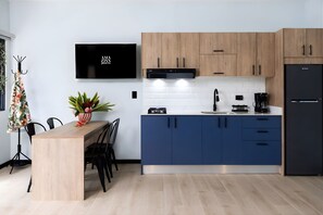 Una cocina moderna con armarios de madera, un refrigerador negro y un comedor con mesa y sillas.