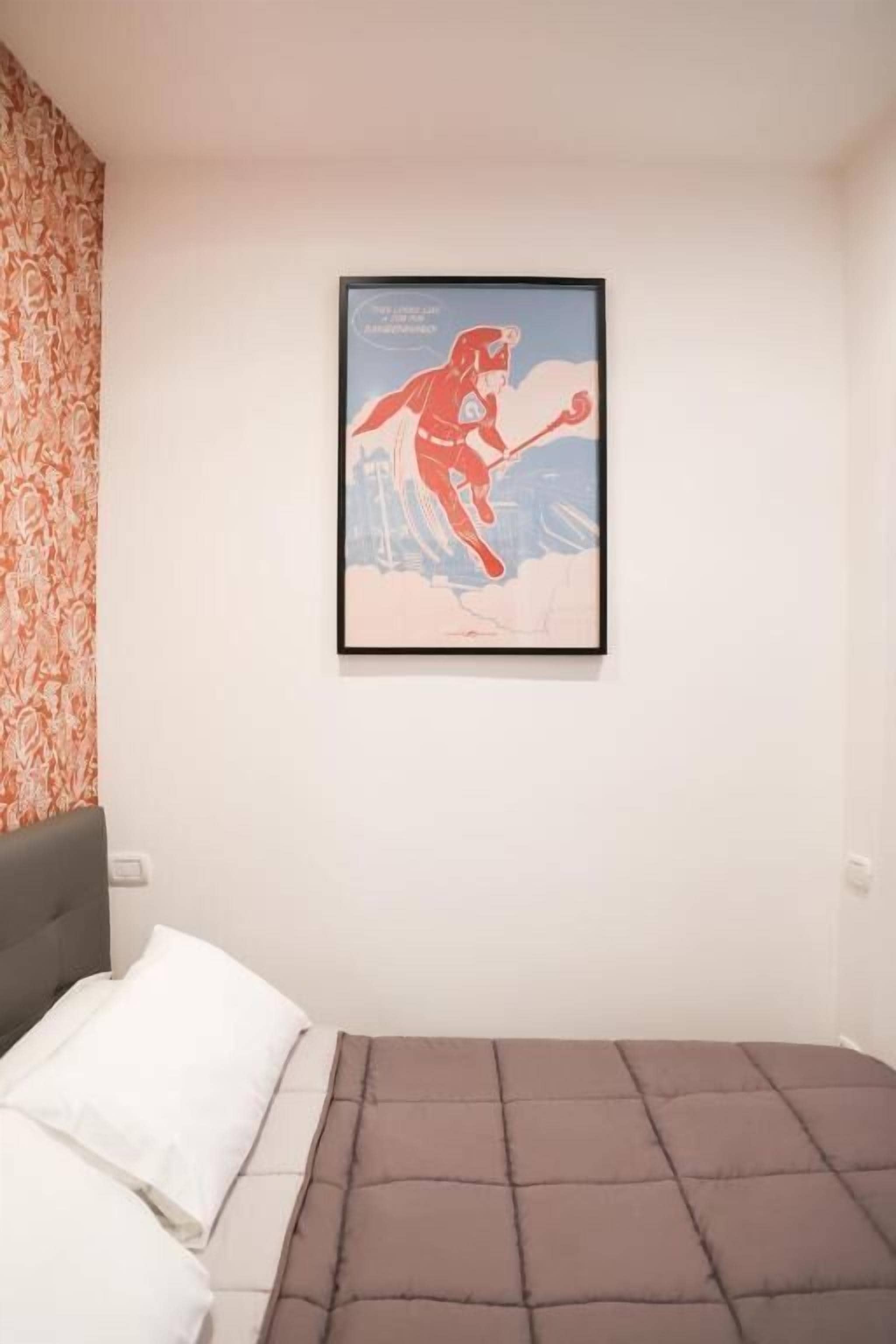 Un dormitorio con una cama, un cuadro en la pared y un papel tapiz estampado.