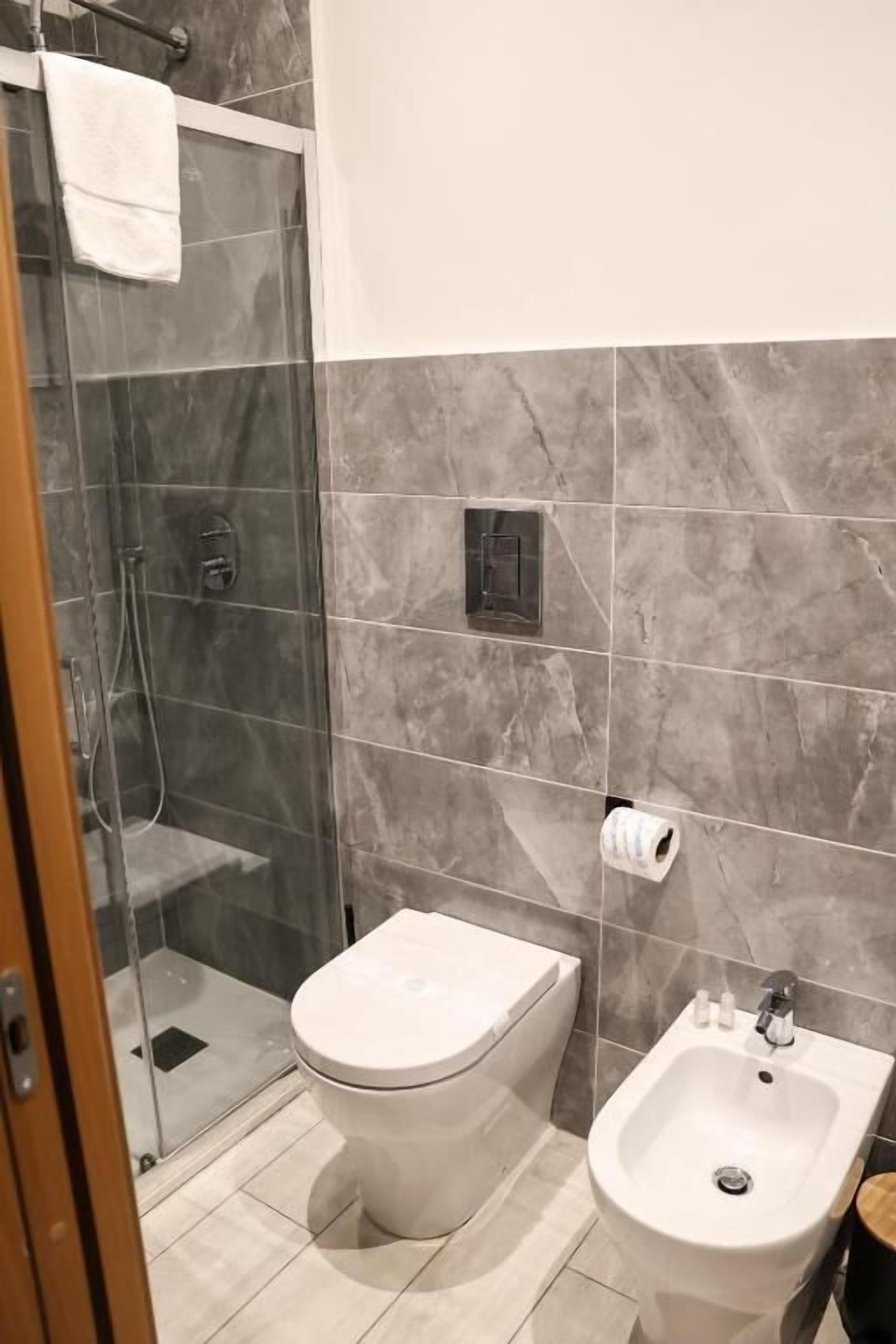 A bathroom with a toilet, bidet, and glass shower enclosure.