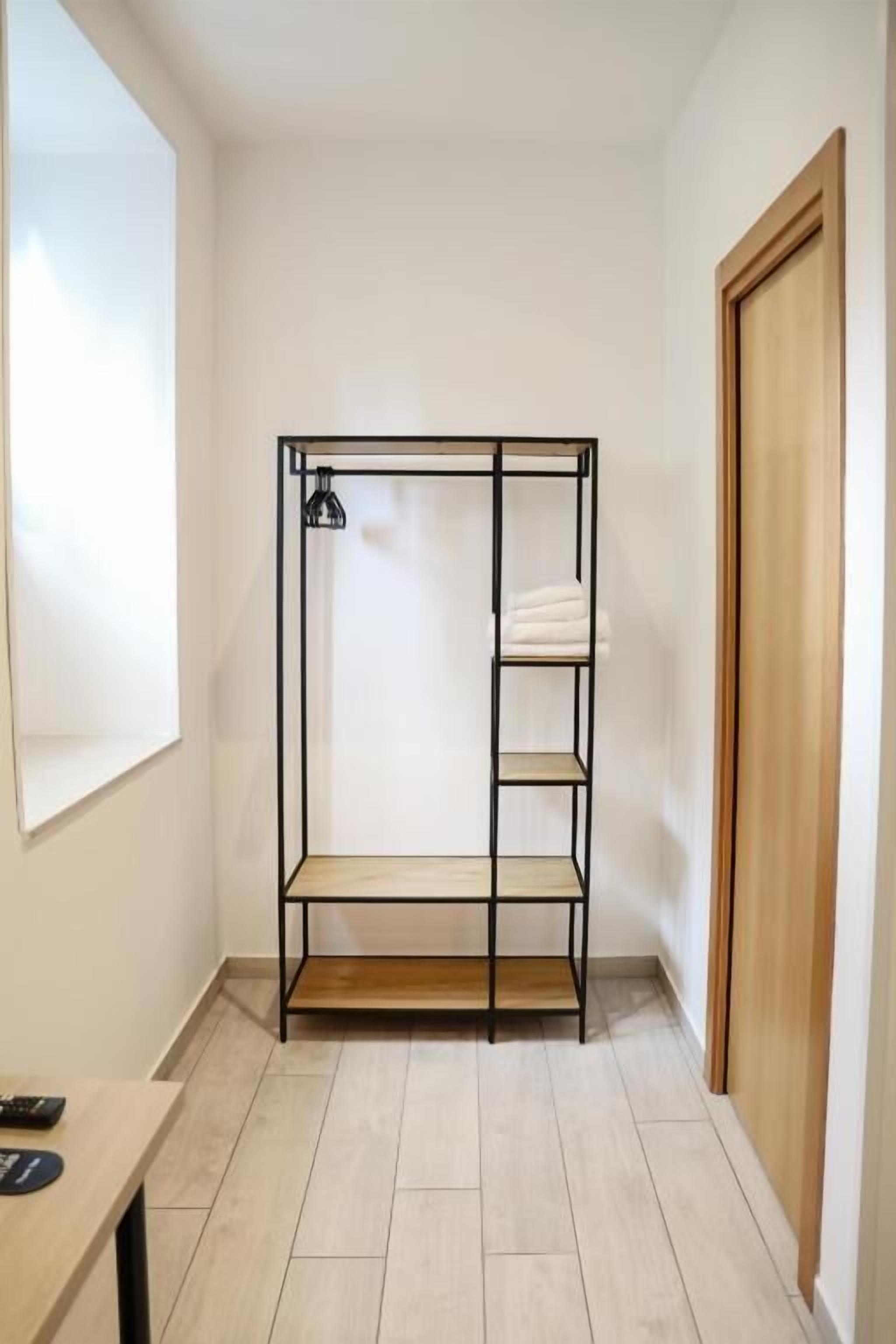 Une pièce avec un lit superposé en métal, une porte en bois et une petite table sur laquelle se trouve une télécommande.