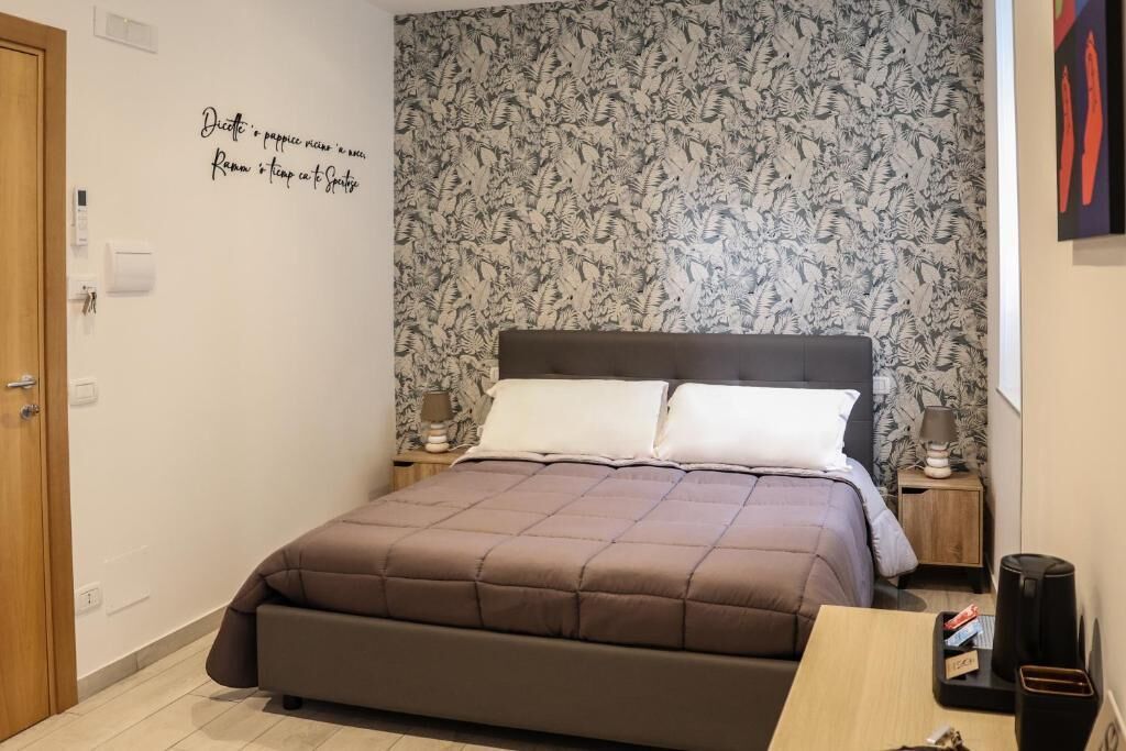 A bedroom with a bed, a nightstand, a wall clock, and a door.