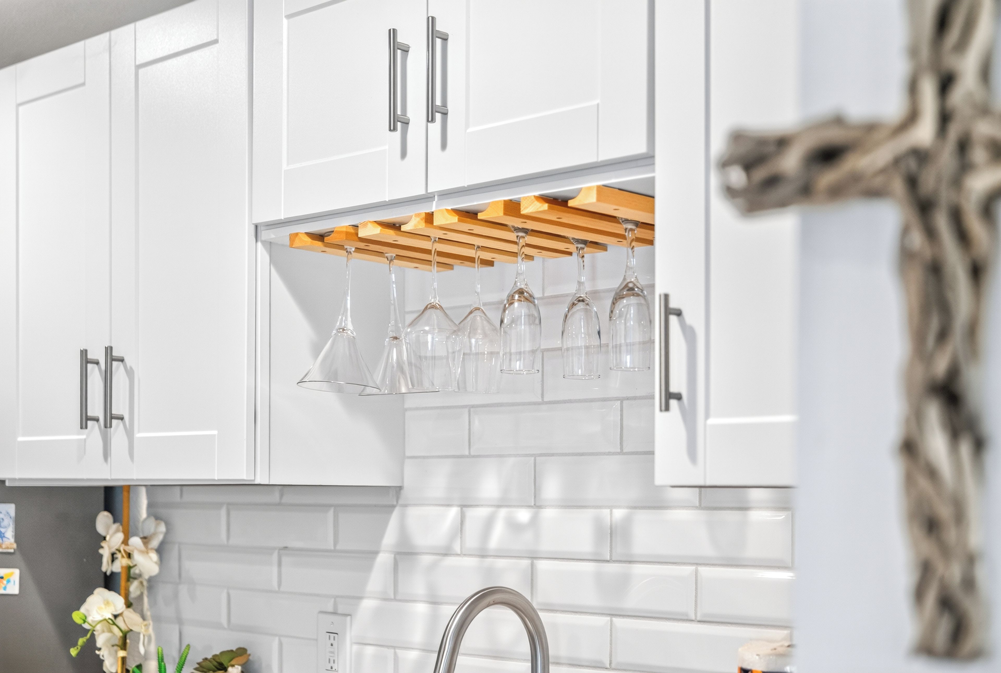 A kitchen with white cabinets, a wooden wine rack, and a sink.