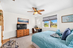 Ein Schlafzimmer mit einem Bett, einem Schreibtisch, einem Stuhl, einem Deckenventilator, einem Fenster mit Blick und einer Wand mit einem Schild.