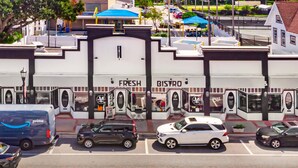 Vista da rua com fachada do Fresh Bistro, uma van de entrega Amazon Prime estacionada e vários carros.