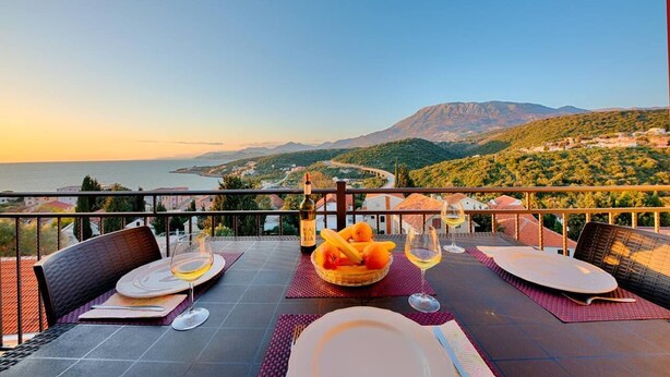 A dining table set for two with a view of the sea and hills. - Apartman ZIS 5L (Opština Bar)