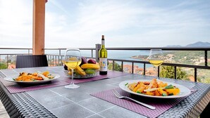 A table set with plates of food, a bottle of wine, and a glass of wine, overlooking a scenic view. - Apartman ZIS 5L (Opština Bar)
