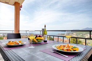 A table set with plates of food, a bottle of wine, and a glass of wine, overlooking a scenic view. - Apartman ZIS 5L (Opština Bar)