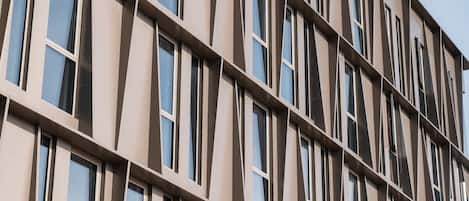 A modern building with a grid of windows and a beige facade.