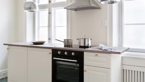 Una cucina con mobili bianchi, un forno nero e pentole in acciaio inossidabile sul piano di lavoro.