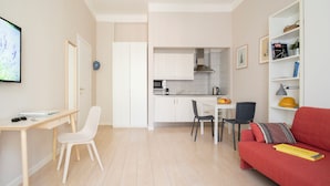 Ein kompakter Wohnraum mit Küchenzeile, Essbereich und Sitzecke mit rotem Sofa.