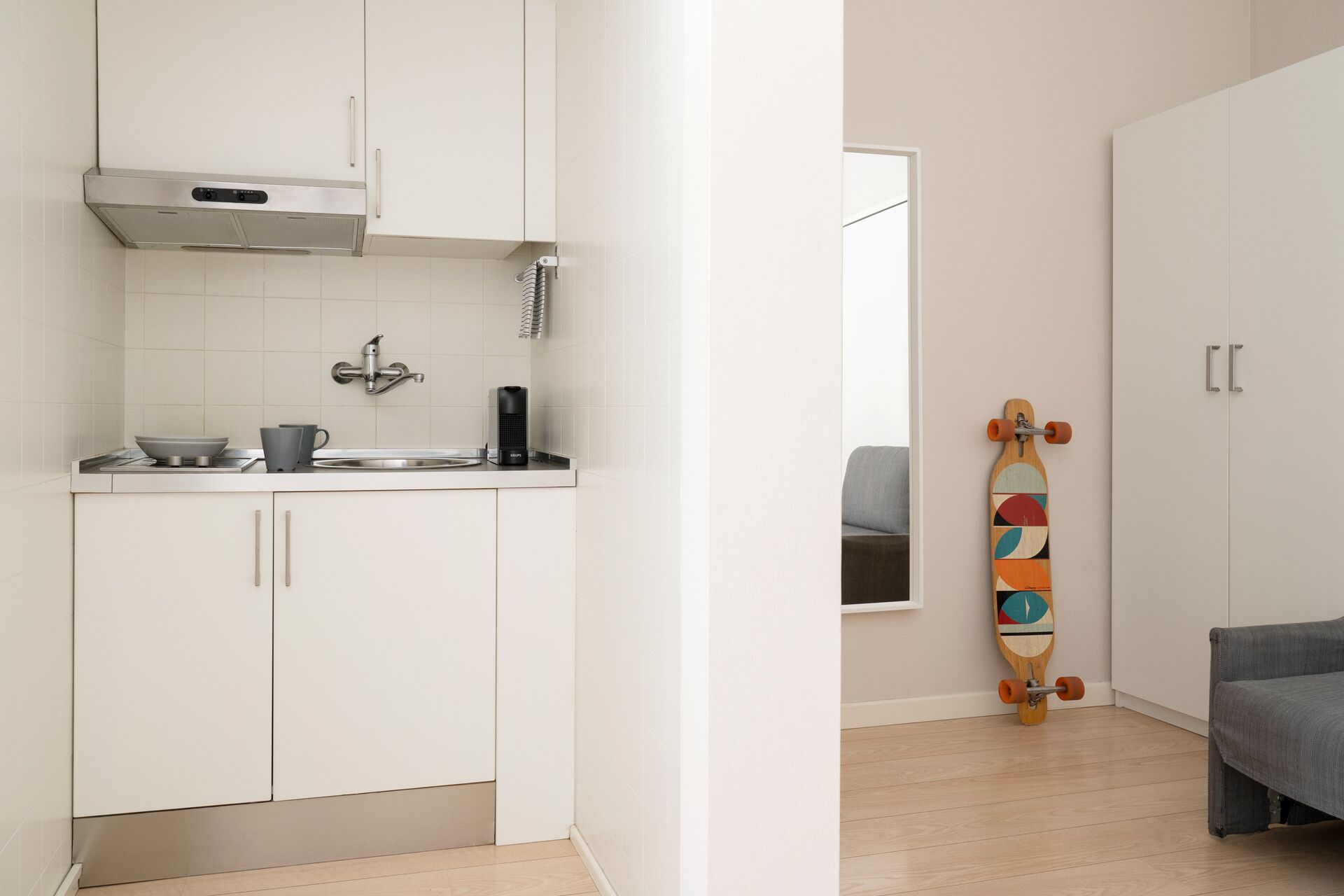 A modern kitchen with white cabinets, a stainless steel range hood, and a built-in dishwasher.