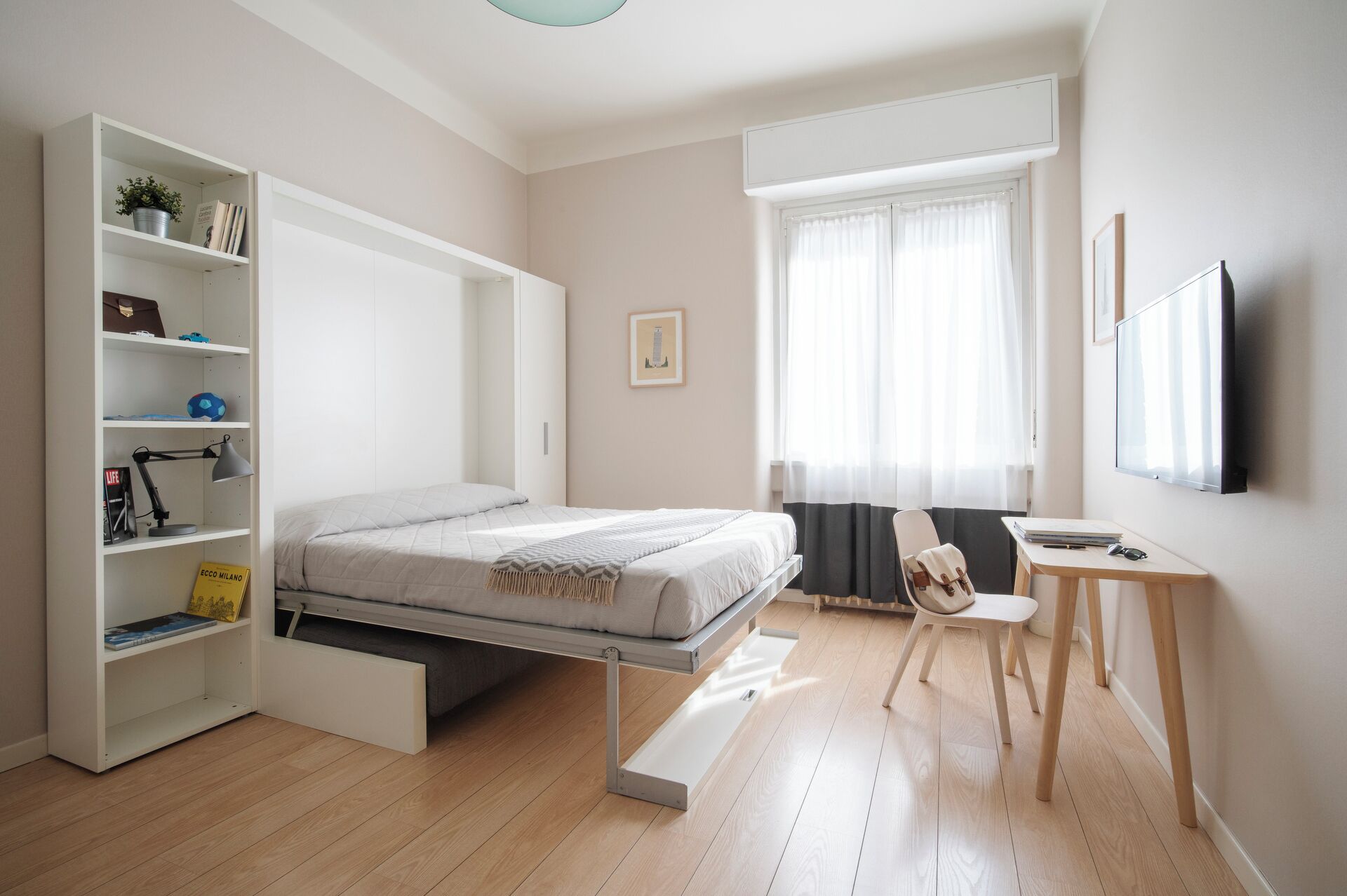 A modern bedroom with a bed, a built-in wardrobe, a desk, and a window with curtains.