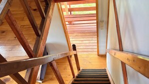 A wooden staircase leading to an upper floor with exposed beams and a view of the outdoors. - Ca bañas Giardino in Lago Ranco (Lago Ranco, Los Ríos)