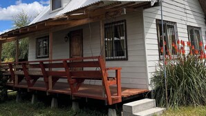 A white wooden house with a porch and a wooden bench. - Ca bañas Giardino in Lago Ranco (Lago Ranco, Los Ríos)