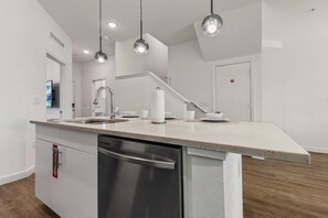 A modern kitchen with a stainless steel dishwasher, a built-in sink, and pendant lighting. - Stylish 6BR townhome w/ private pool•Near parks (Davenport)