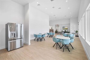 A modern kitchen with stainless steel appliances, a water dispenser, and a seating area with round tables and chairs. - Stylish 6BR townhome w/ private pool•Near parks (Davenport)