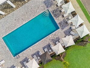 An aerial view of a rectangular swimming pool surrounded by white umbrellas and lounge chairs. - Stylish 6BR townhome w/ private pool•Near parks (Davenport)