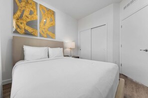 Ein Hotelzimmer mit einem großen Bett, einem Nachttisch mit Lampe und einem Kleiderschrank.