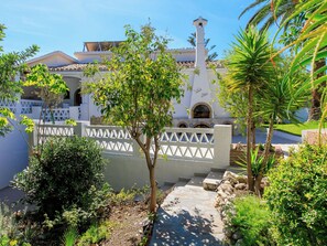 A courtyard with a white building, a stone pathway, and lush greenery. - Vacation home Monet by Interhome (Nerja)