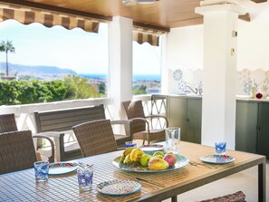 A dining area with a table set for two, featuring wicker chairs, a view of the landscape, and a tiled backsplash. - Vacation home Monet by Interhome (Nerja)