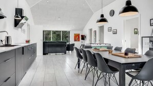 Una cocina moderna con comedor, que incluye una mesa de fútbol de mesa, un ventanal grande y un techo alto.