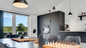 Una cocina moderna con una gran mesa de comedor, un juego de ajedrez y vistas al exterior.